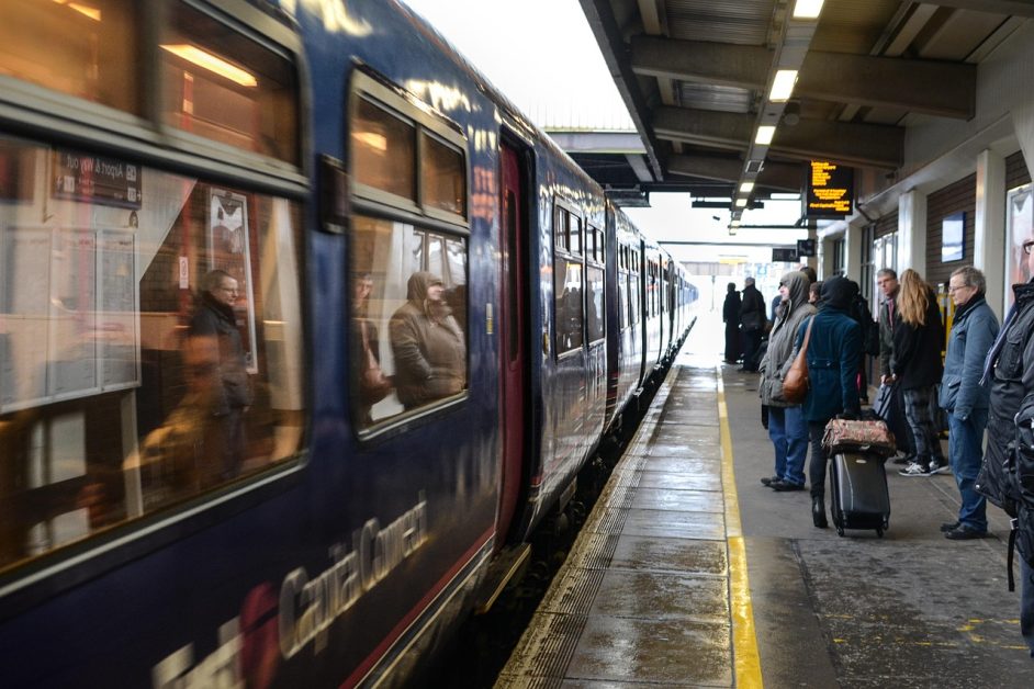 el anden de una estación de trenes con gente abrigada esperando y el tren parado con las puertas cerradas