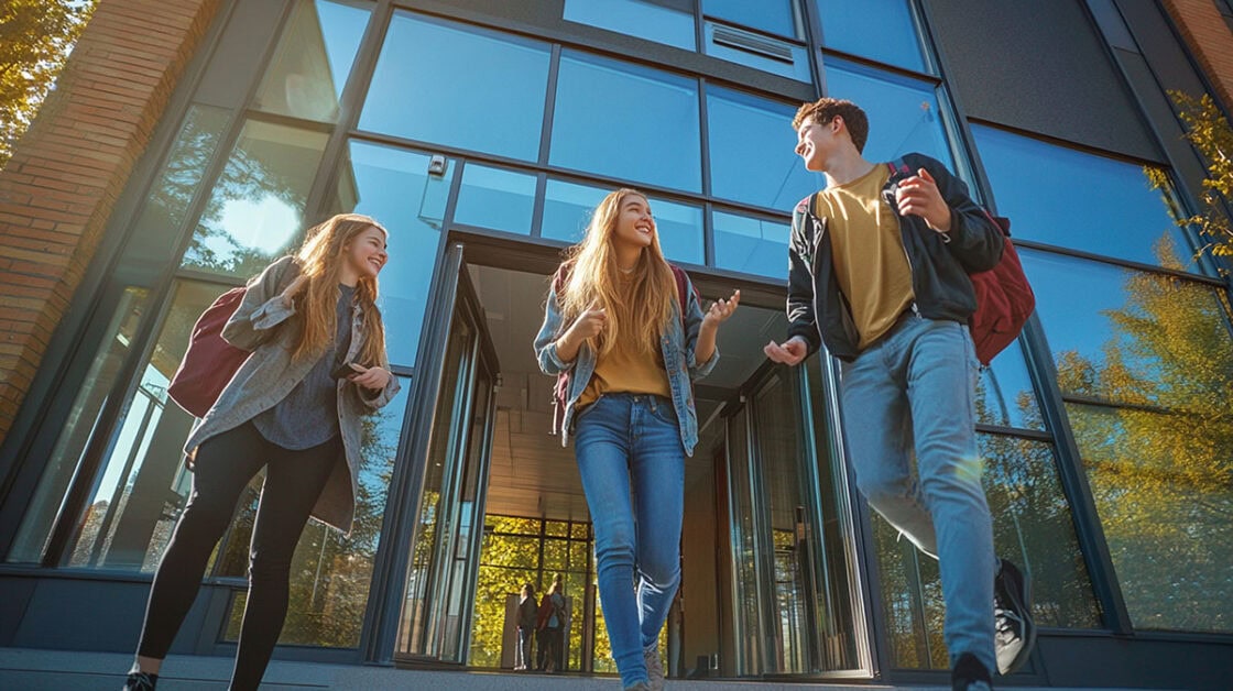 dos mujeres y un hombre con mochilas saliendo de una puerta acristalada